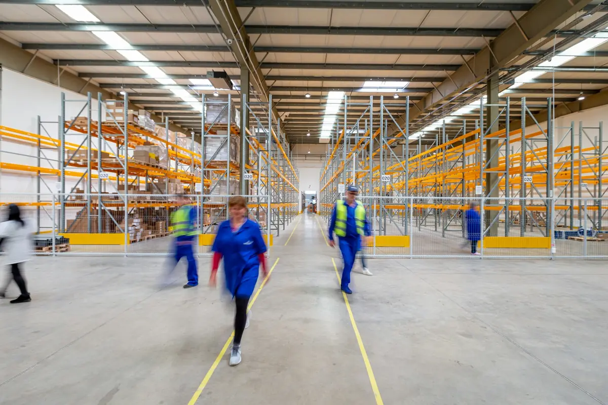 Workers walking through a warehouse aisle.