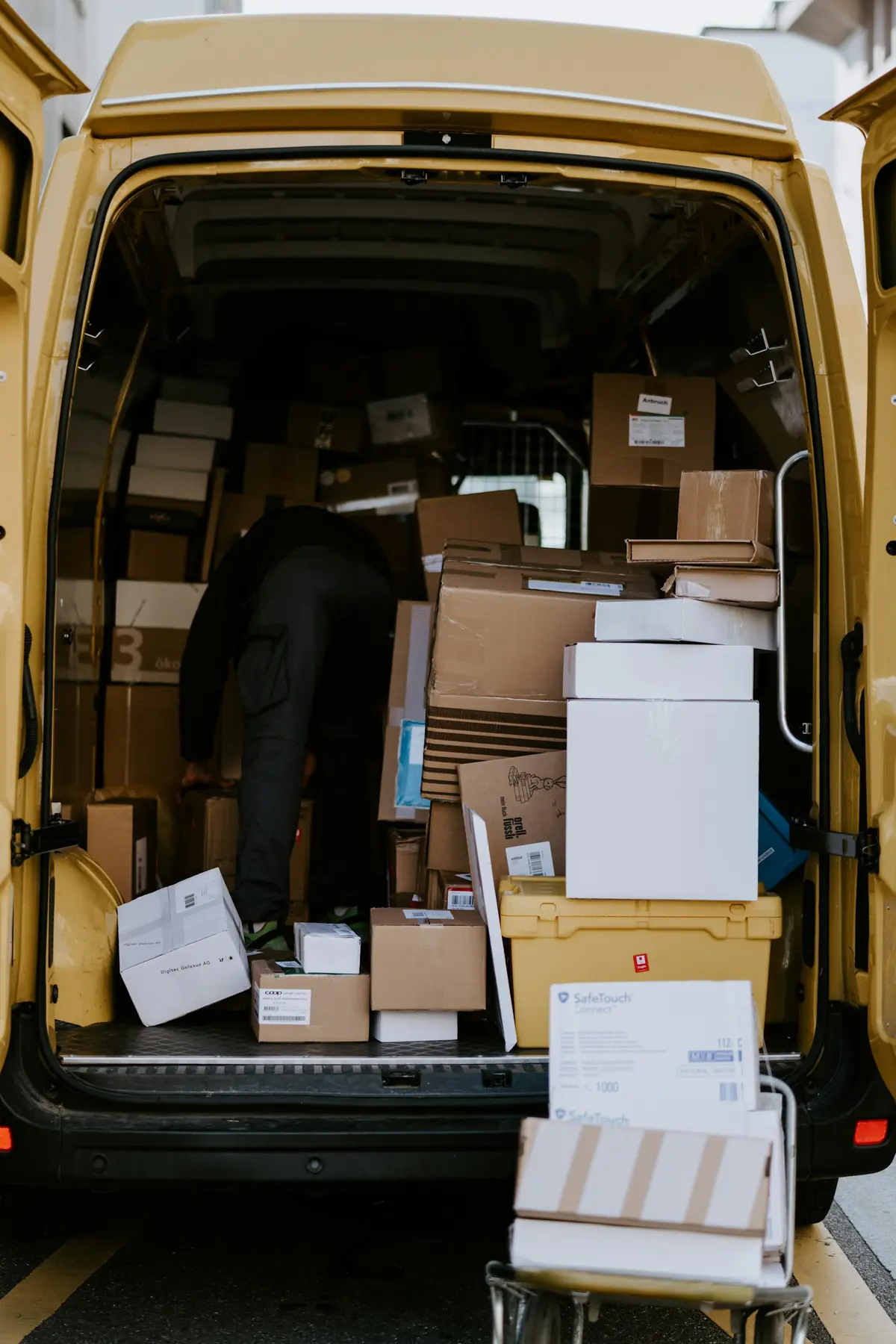 A person loading cardboard boxes into a delivery van.