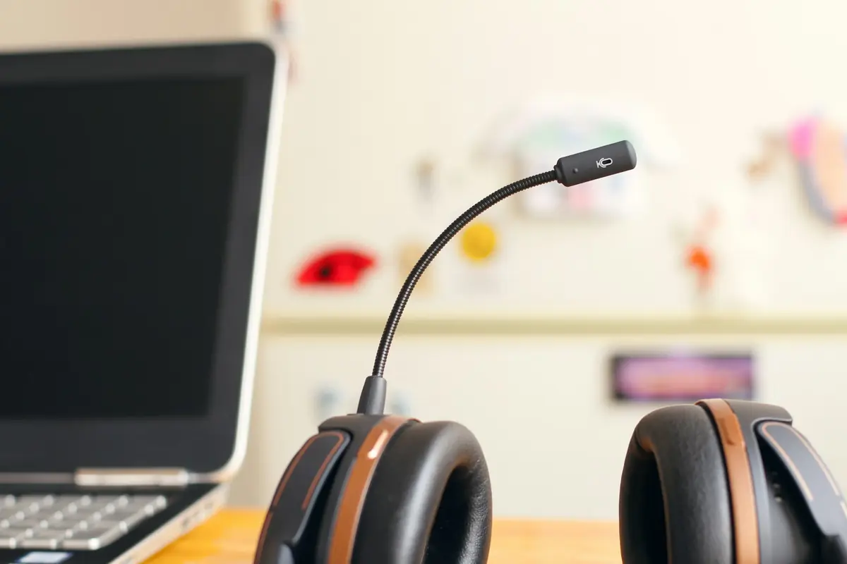 A headset beside a laptop on a desk.